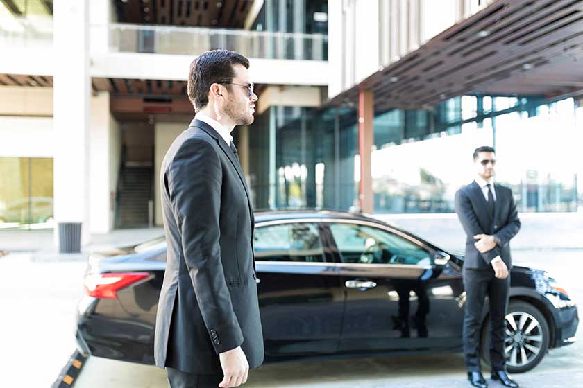 Executive protection agents standing by car while doing their duty in city