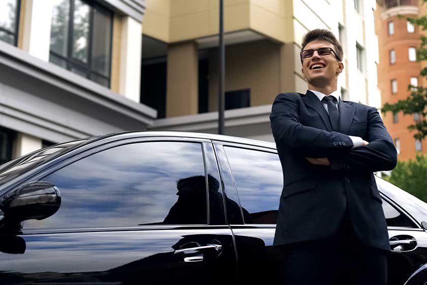 Happy young male standing by new luxurious car, office worker getting promotion