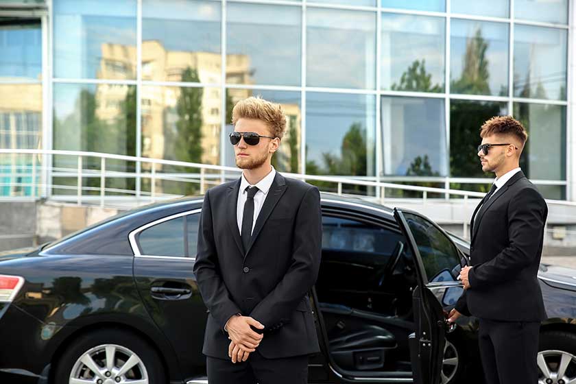 Professional bodyguards near car outdoors